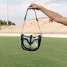 Image shows model's hand holding the Margaret Clear & Black Purse in front of grass field.