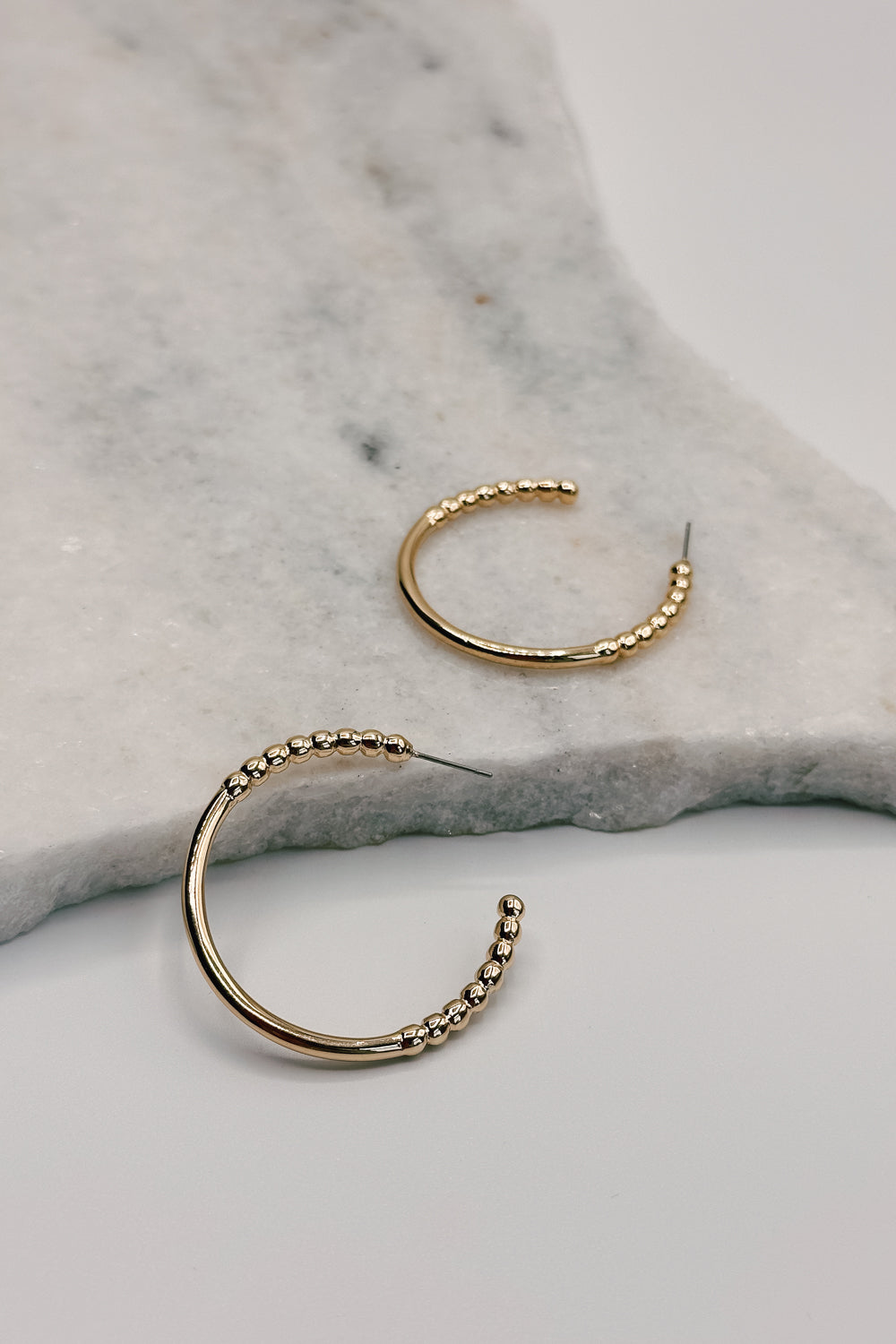 Close up view of the Alaina Gold Dipped Bead Hoop Earring. the earring features gold dipped half beaded hoops