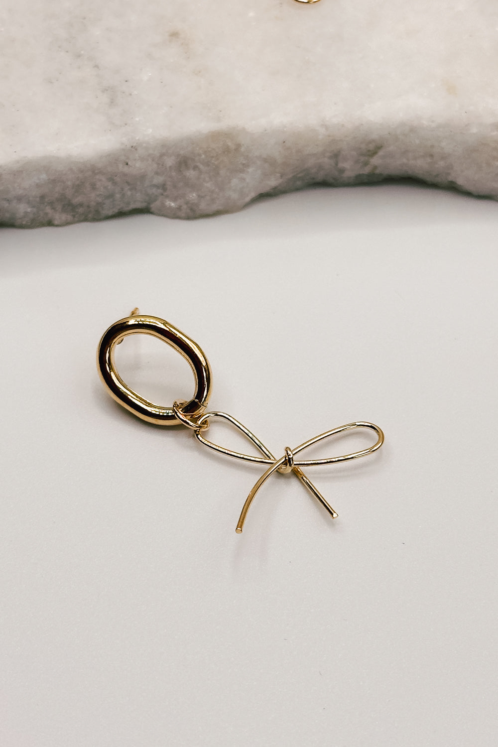 close up view of the Valeria Gold Dipped Bow Dangle Earring which features gold dipped bow shaped dangle earrings