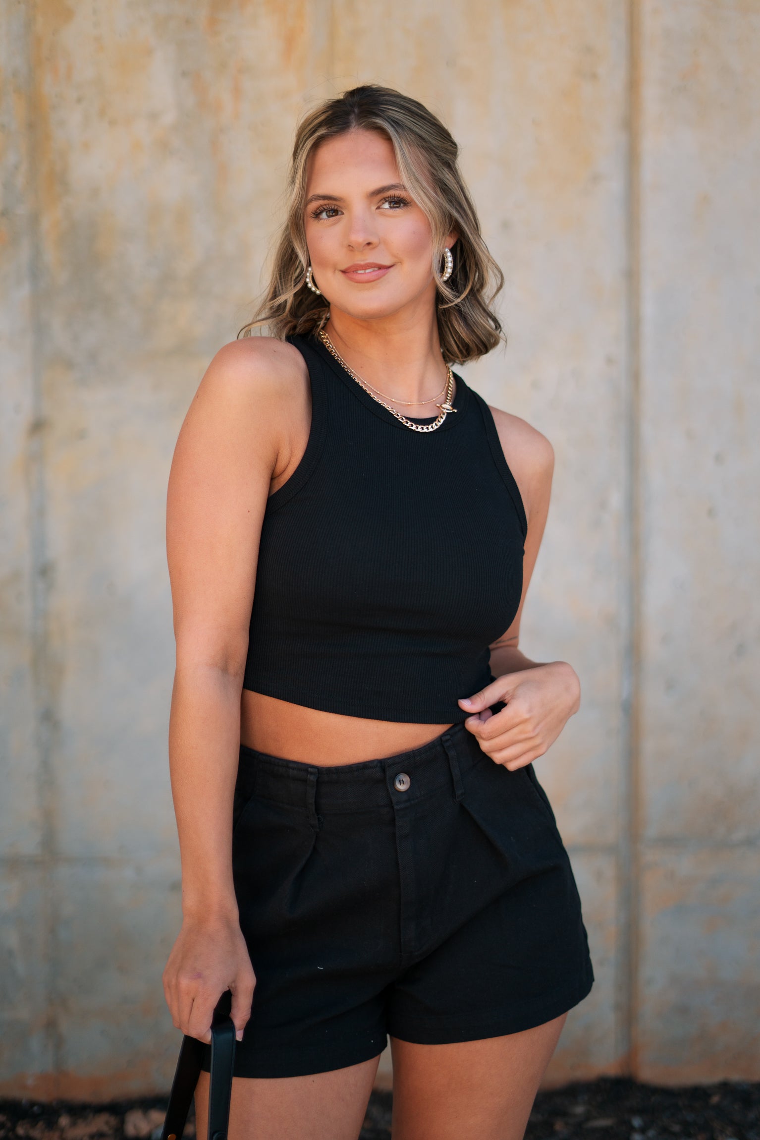 Front view of female model wearing the Andrea Black Ribbed Sleeveless Tank which features Black Ribbed Fabric, Cropped Waist, Round Neckline and Sleeveless