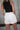 Back view of female model wearing the Katherine Tortoise Buttoned Shorts in White which features Cotton Fabric, Two Front Pockets, Two Back Pockets, Belt Loops and Front Zipper with Tortoise Button Closure