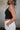 Side view of female model wearing the Julie Ribbed Sleeveless Tank in Black which features Ribbed Lightweight Fabric, Round Neckline and Sleeveless.