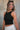 Frontal side view of female model wearing the Julie Ribbed Sleeveless Tank in Black which features Ribbed Lightweight Fabric, Round Neckline and Sleeveless.