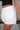 Side view of female model wearing the Katherine Tortoise Buttoned Shorts in White which features Cotton Fabric, Two Front Pockets, Two Back Pockets, Belt Loops and Front Zipper with Tortoise Button Closure