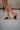 Right side view of female model wearing the B.O.C. Born Concept Sunny Wedge Sandal in Black which features Black Faux Leather Upper, Slip-On Style and Criss-Cross Strap & Toe Wrap Detail