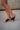 Right side view of female model wearing the B.O.C. Born Concept Sunny Wedge Sandal in Black which features Black Faux Leather Upper, Slip-On Style and Criss-Cross Strap & Toe Wrap Detail