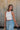 Frontal side view of female model wearing the Julie Ribbed Sleeveless Tank in White which features Ribbed Lightweight Fabric, Round Neckline and Sleeveless.