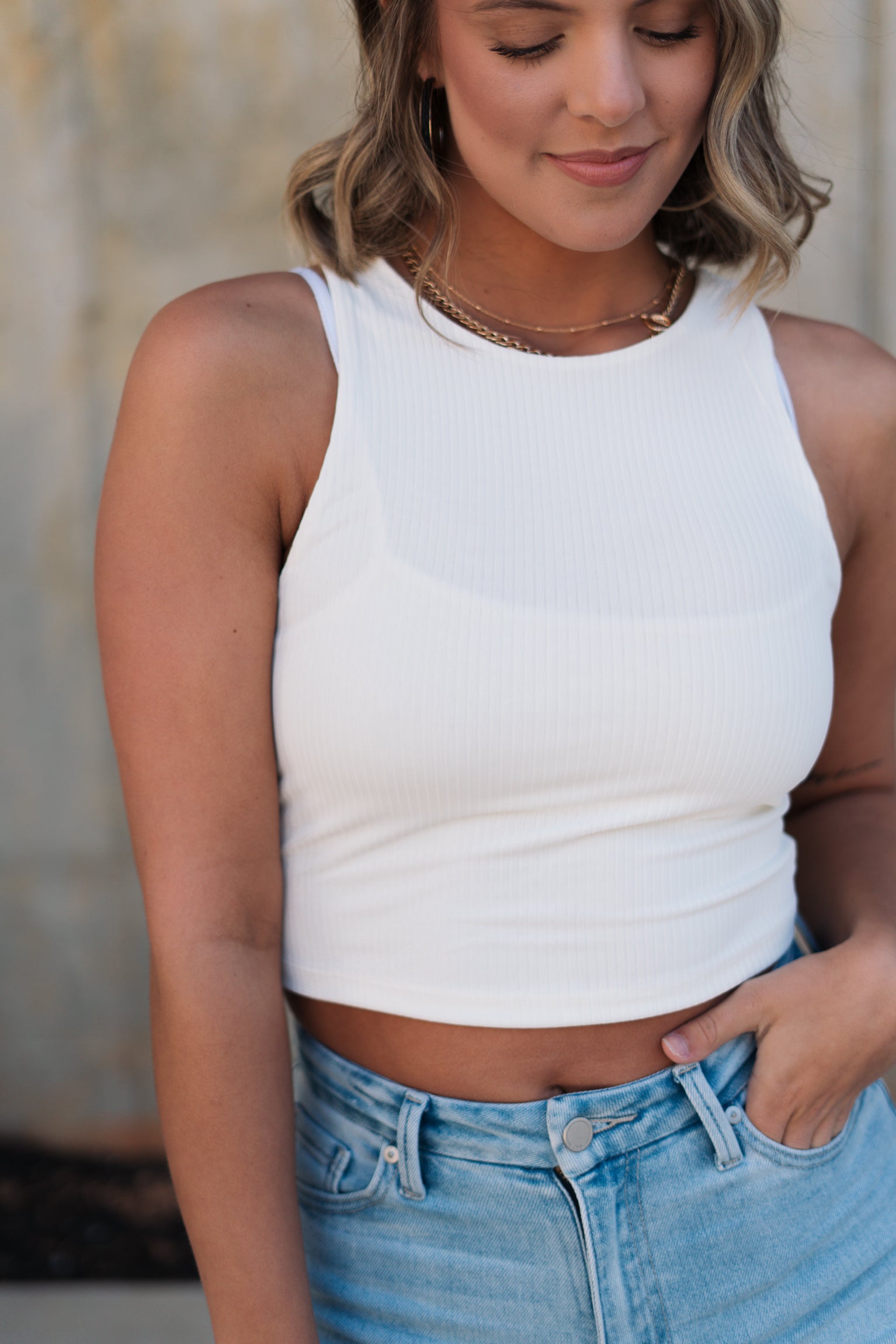 Close up view of female model wearing the Julie Ribbed Sleeveless Tank in White which features Ribbed Lightweight Fabric, Round Neckline and Sleeveless.