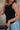 Side view of female model wearing the Brielle Black Sleeveless Tank which features Black Lightweight Fabric, Round Neckline and Sleeveless