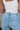Close-up back view of female model wearing the Kristen Light Wash Wide Leg Jeans that features wide cropped legs, light wash denim, belt loops, pockets, and a zipper/button fly. Worn with white tank top
