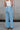 Back view of female model wearing the Kristen Light Wash Wide Leg Jeans that features wide cropped legs, light wash denim, belt loops, pockets, and a zipper/button fly. Worn with white tank top