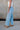 Side view of female model wearing the Kristen Light Wash Wide Leg Jeans that features wide cropped legs, light wash denim, belt loops, pockets, and a zipper/button fly. Worn with white tank top