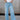 Front view of female model wearing the Kristen Light Wash Wide Leg Jeans that features wide cropped legs, light wash denim, belt loops, pockets, and a zipper/button fly. Worn with white tank top