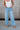 Front view of female model wearing the Kristen Light Wash Wide Leg Jeans that features wide cropped legs, light wash denim, belt loops, pockets, and a zipper/button fly. Worn with white tank top