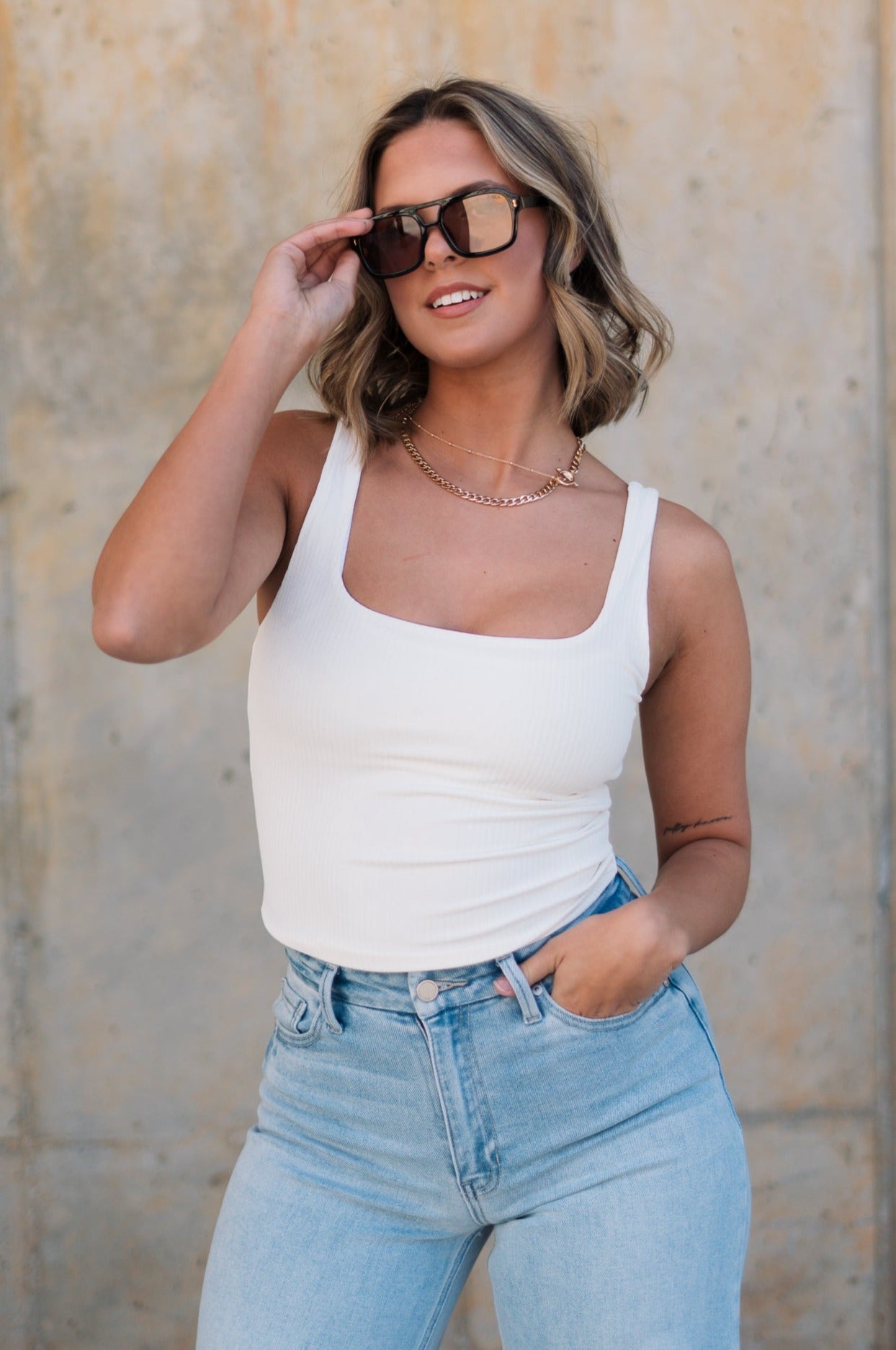 Front view of female model wearing the Leigh Square Neckline Sleeveless Tank which features Ribbed Lightweight Fabric, Square Neckline and Sleeveless. the tank is available in white and black.