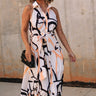 Full body front view of female model wearing the Elina Printed Button Front Midi Dress that has ivory, black, and orange geometric printing, a tie belt, a button up front, a collared sleeveless neckline, and midi length.