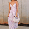 Full body front view of female model wearing the Bridget Lavender Watercolor Midi Dress that has a lavender watercolor floral pattern, a corset top, thin straps, and midi length
