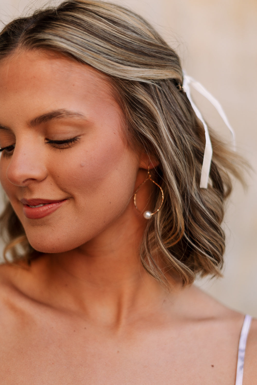 Side view of female model wearing the Elizabeth Gold Pearl Hoop Dangle Earring which features open hammered, gold hoop with single pearl detail