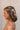 Side view of female model's hair; model is wearing the Melrose Hair Bow Barette in cream that has a barrette with a thin ivory bow..