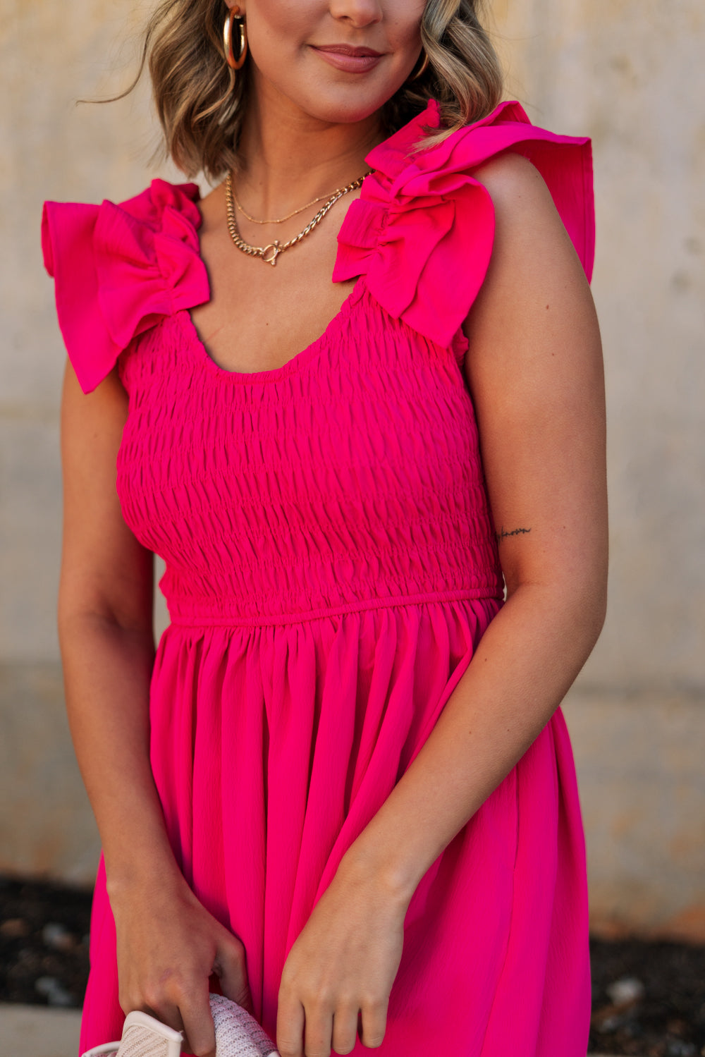 Upper body front view of female model wearing the Kristina Pink Smocked Sleeveless Midi Dress that has hot pink fabric, side slit pockets, midi length, smocked upper, a scoop neckline, and ruffled straps.