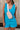 Front view of female model wearing the Chelsea Blue Sleeveless Romper that has bright blue fabric, a v neck, side pockets, and thick straps. Model has beige sling bag on.