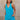 Front view of female model wearing the Chelsea Blue Sleeveless Romper that has bright blue fabric, a v neck, side pockets, and thick straps. Model has hands in pockets.