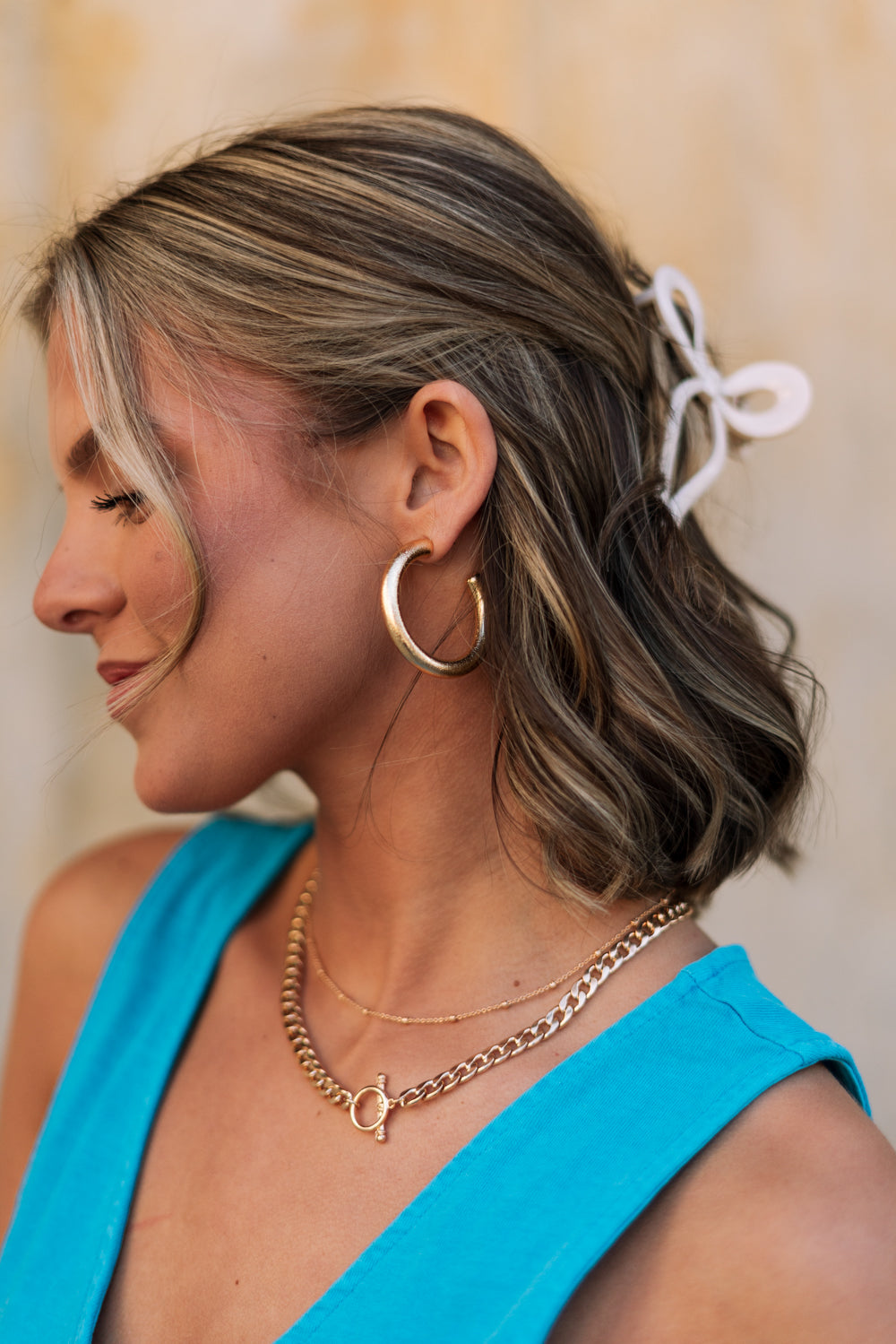 Side view of female model wearing the Angela Gold Open Hoops which features medoium, open gold hoops