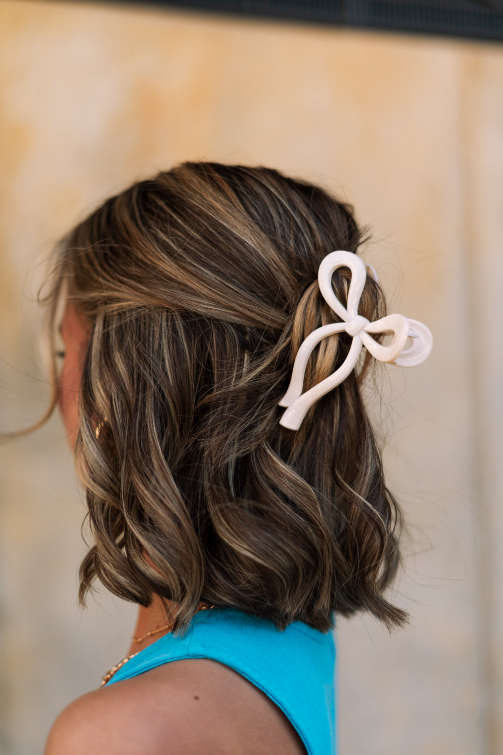 Side view of female model's hair; model is wearing the Zoey Bow Claw Clip in Cream.