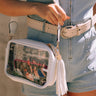 Image shows up close image of model wearing the Tiffany Clear Purse in White that has a clear rectangle body, white exterior, a white strap, and a white fringe tassel.
