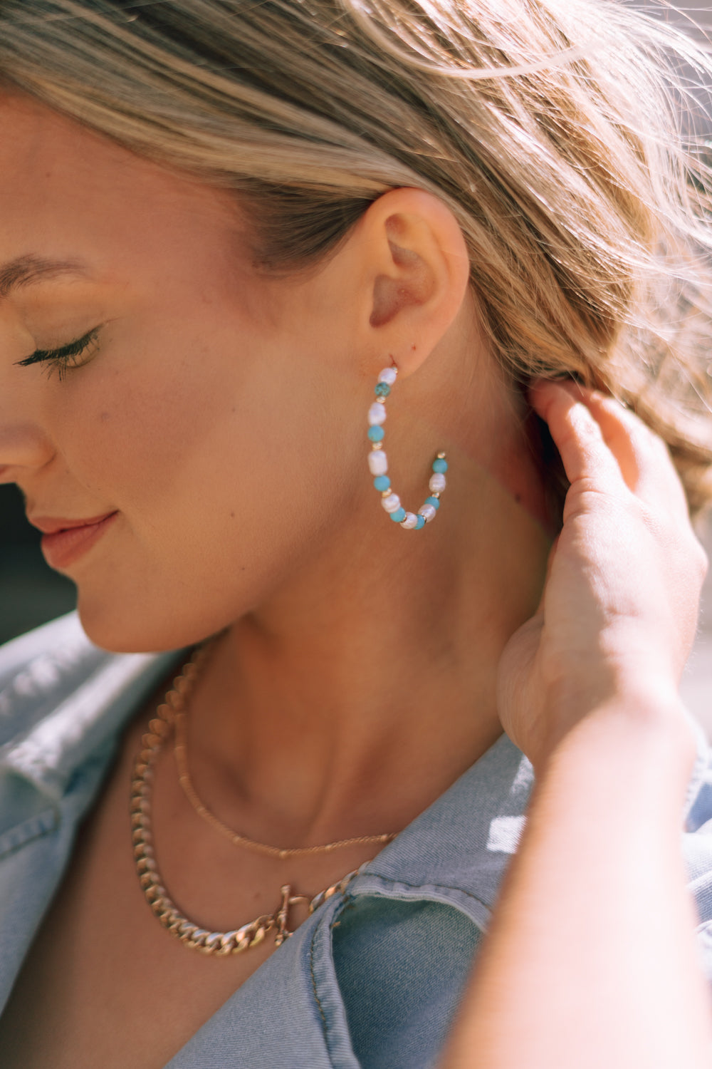 Side view of female model wearing the Avianna Turquoise & Pearl Hoop Earring which features large, open hoops with gold, turquoise and pearl beads