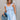 front view of female model wearing the Taylor Light Wash Denim Romper that has light wash denim fabric, straps with frayed hems, elastic waist, neckline pleating, and side pockets.
