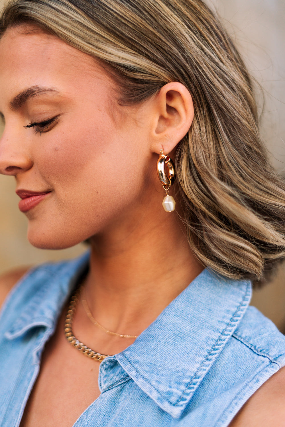 Side view of female model wearing the Patricia Gold Hoop Pearl Dangle Earring which features Gold closed hoops with pearl dangle attachment