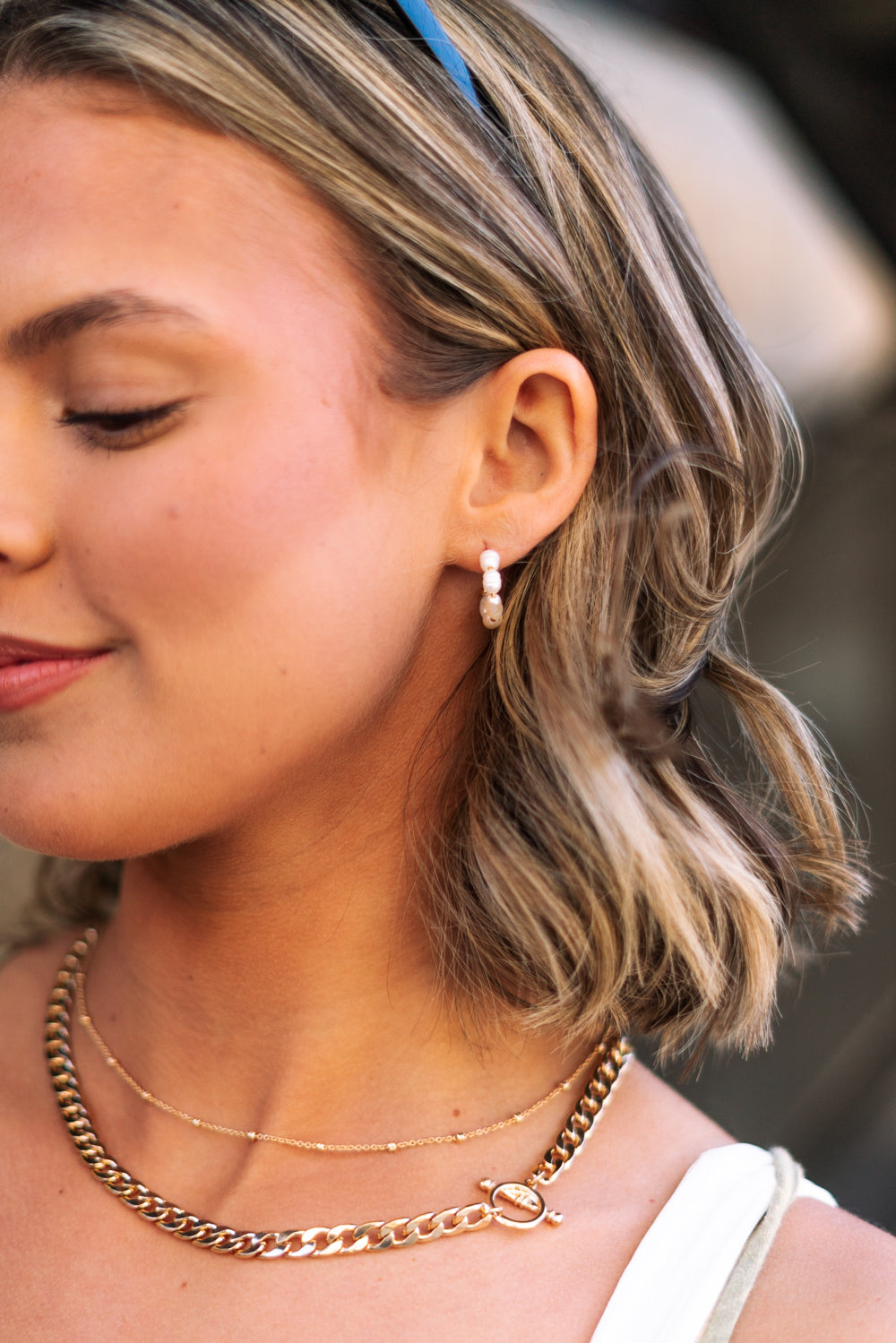 Side view of female model wearing the Meadow Mini Pearl Hoop Earring which features mini, open gold hoops with pearls