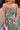 Close-up upper body front view of female model wearing the Leilani Printed Sleeveless Maxi Dress that has a multi-colored green, red, pink, purple, and yellow print, spaghetti straps, a smocked upper, and a tiered skirt.