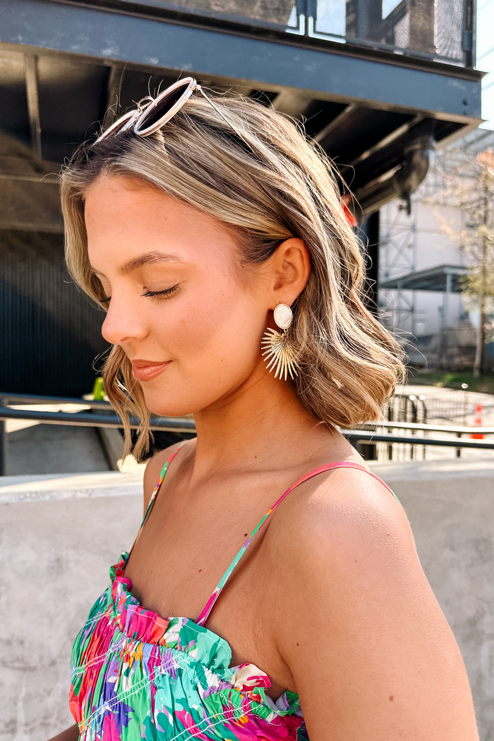 Side view of female model wearing the Penelope Gold & Opal Starburst Dangle Earring which features Gold stabrust earrings with opal stone design