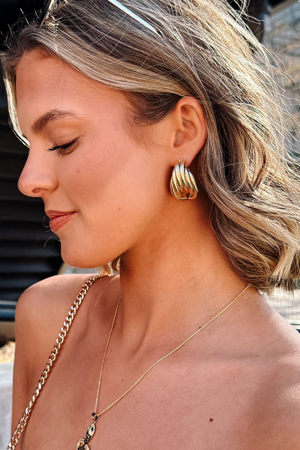Side view of female model wearing the Stella Gold Rope Dangle Stud Earring which features oversized, gold rope studs