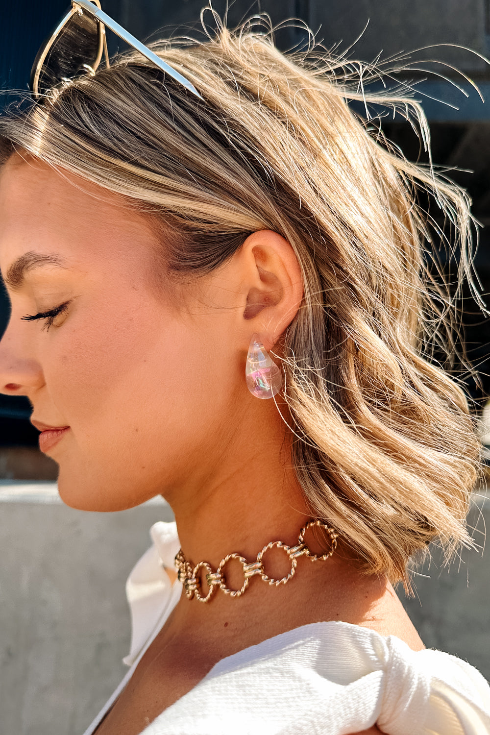 Side view of female model wearing the Mila Iridescent Scoop Teardrop Stud Earring which features iridescent teardrop studs