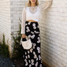 Full body front view of female model wearing the Marley Black Floral Satin Midi Skirt, paired with a cream sweater