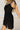 Side view of female model wearing the Livia Black Denim Dress that has black denim, tie straps, and back zipper.
