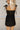 Back view of female model wearing the Livia Black Denim Dress that has black denim, tie straps, and back zipper.