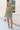 Full body front view of female model wearing the Abigail Olive Denim Dress that has olive denim fabric, a button up front, pockets, and collar.