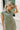 Front view of female model wearing the Abigail Olive Denim Dress that has olive denim fabric, a button up front, pockets, and collar.