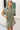 Front view of female model wearing the Abigail Olive Denim Dress that has olive denim fabric, a button up front, pockets, and collar.