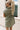 Back view of female model wearing the Abigail Olive Denim Dress that has olive denim fabric, a button up front, pockets, and collar.