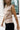 Side view of female model wearing the Cecilia Taupe Padded Shoulder Tank that has taupe knit fabric, a round neck, and padded sleeveless shoulders.