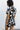 Upper body back view of female model wearing the Valerie Black & White Short Sleeve Romper that has a black and white abstract print, short sleeves, a collar, button up front, and elastic waist with tie.