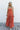 Full body front view of female model wearing the Jules Orange Printed Wide Leg Jumpsuit that has orange printed fabric, thin straps, and wide legs.