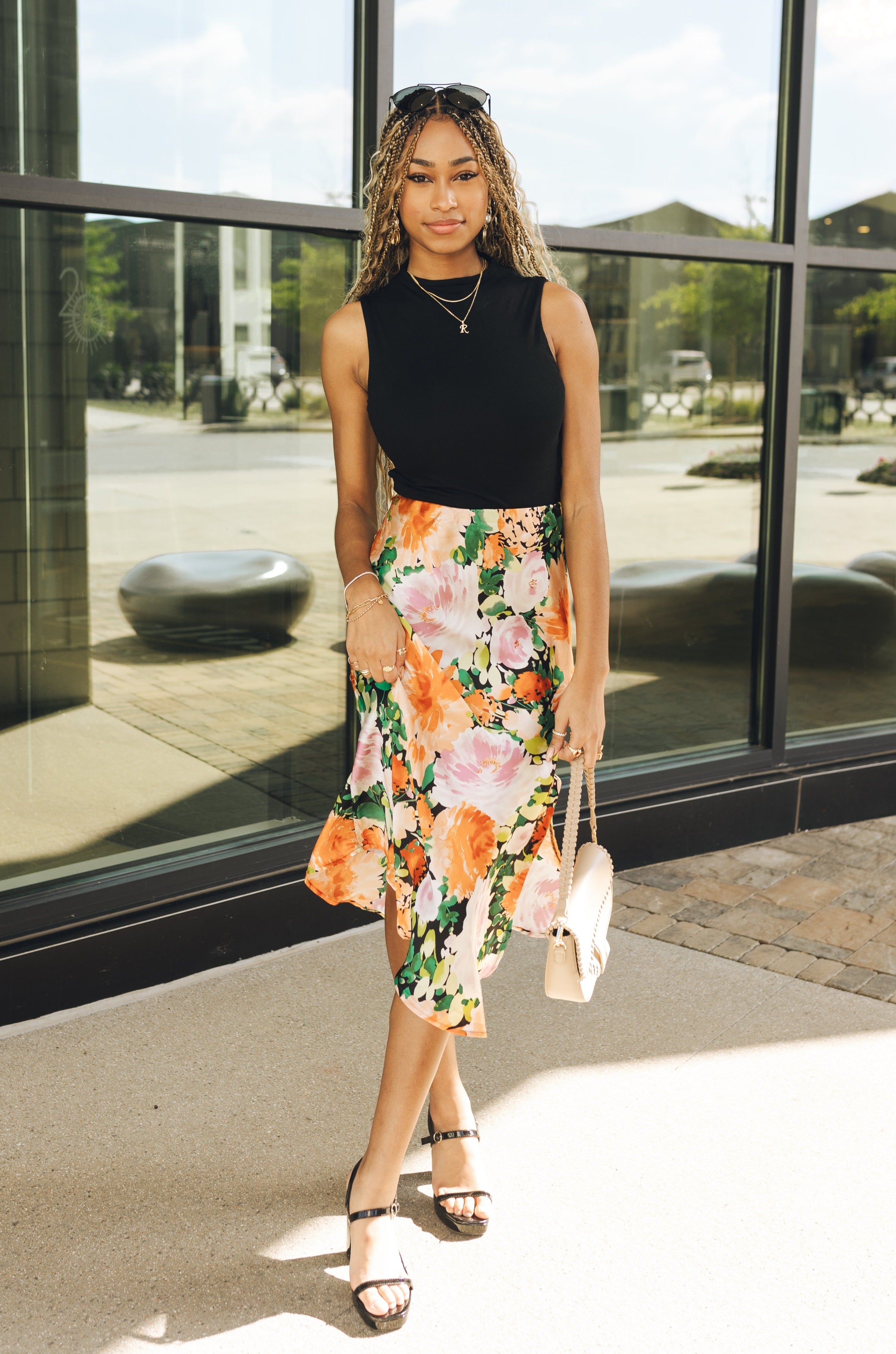 Full body view of model wearing the Amalia Black Floral Midi Skirt. This is a black midi skirt with multicolored floral pattern, satin. 