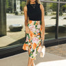 Full body view of model wearing the Amalia Black Floral Midi Skirt. This is a black midi skirt with multicolored floral pattern, satin. 