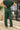 Close up back view of model wearing the Naya Forest Green Pants. These are green pants with a wide leg look.